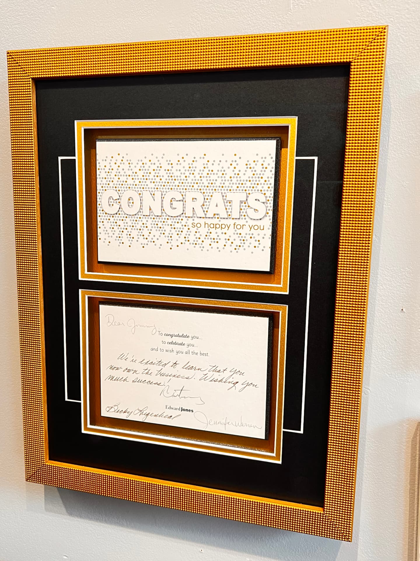 Two keepsake cards custom framed with black and gold layered mats inside a textured gold frame
